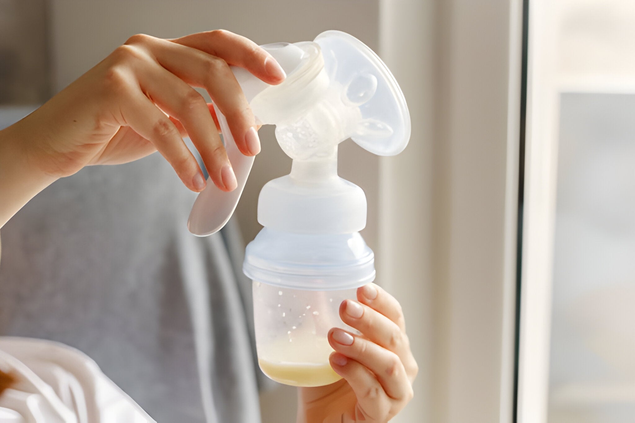 Mother holding her recently pumped breast milk in a baby bottle.