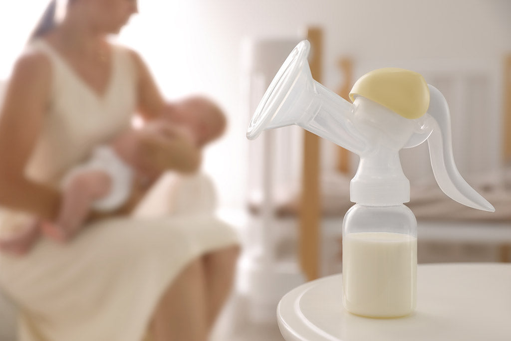 Closeup of a breast pump, with mother and child in the background.