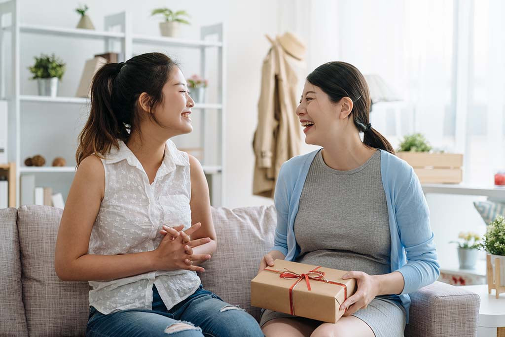 A woman giving her pregnant friend a Mother’s Day gift.